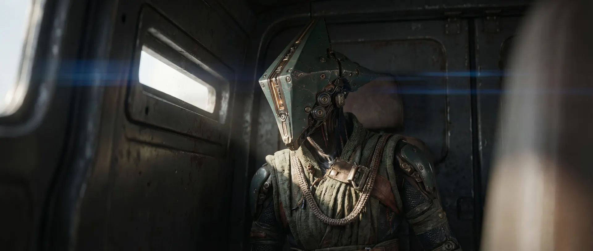 A figure in a battered, angular metal mask stands in the gloom of an old train carriage.